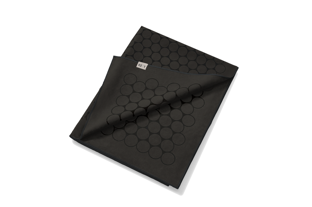 The GECKO TOUCH – Nightfall yoga towel features a simple yet elegant symmetrical circular pattern made of tactile silicone, offering a unique wet/dry grip. It comes with a sleek black graphite base with contrasting colored stitching and is made using an eco-friendly, dye-free process.