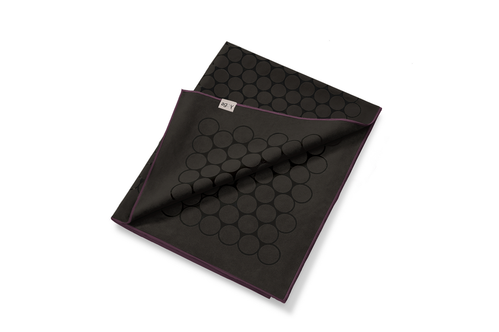 The GECKO TOUCH – Nightfall yoga towel features a simple yet elegant symmetrical circular pattern made of tactile silicone, offering a unique wet/dry grip. It comes with a sleek black graphite base with contrasting colored stitching and is made using an eco-friendly, dye-free process.