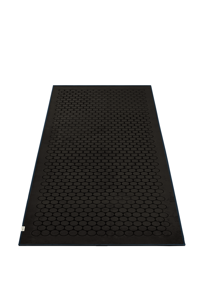 The GECKO TOUCH – Nightfall yoga towel features a simple yet elegant symmetrical circular pattern made of tactile silicone, offering a unique wet/dry grip. It comes with a sleek black graphite base with contrasting colored stitching and is made using an eco-friendly, dye-free process.