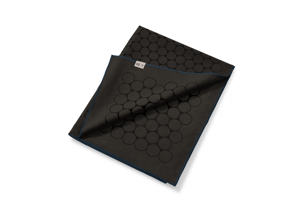 The GECKO TOUCH – Nightfall yoga towel features a simple yet elegant symmetrical circular pattern made of tactile silicone, offering a unique wet/dry grip. It comes with a sleek black graphite base with contrasting colored stitching and is made using an eco-friendly, dye-free process.