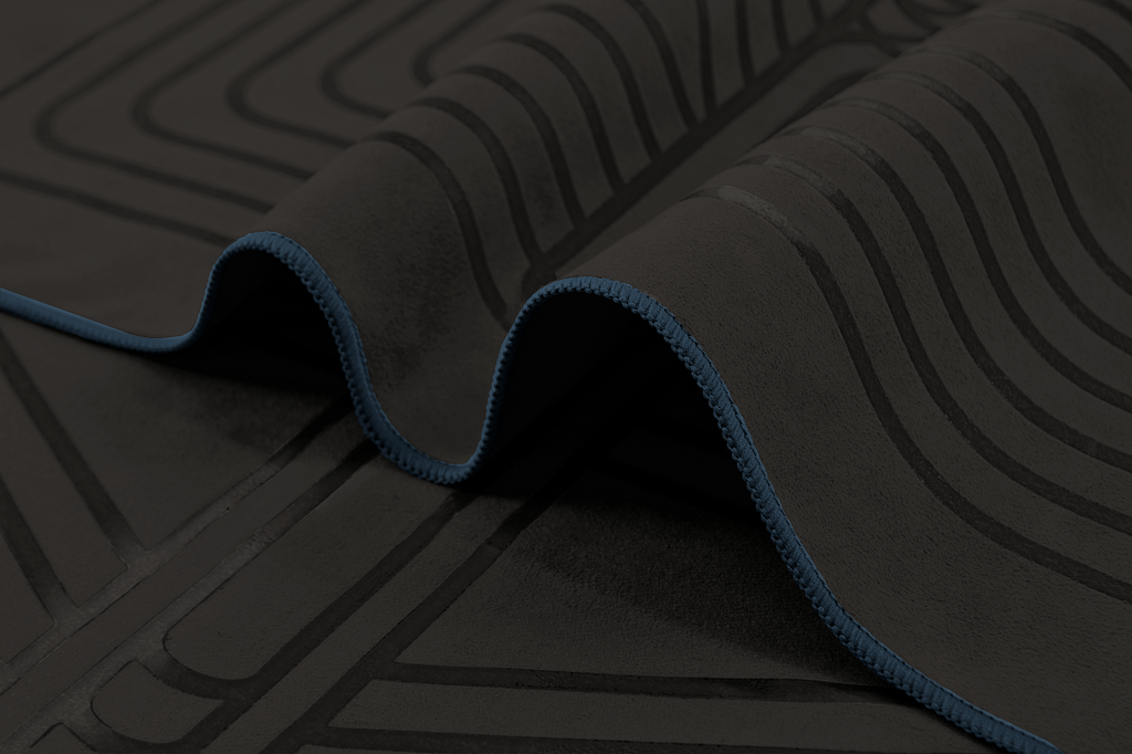 The GECKO WARRIOR – Nightfall yoga towel features a unique wet/dry grip Focus Alinement™ pattern made of tactile silicone, inspired by but not directly taken from ancient warrior cultures. It comes with a sleek black graphite base with contrasting colored stitching and is made using an eco-friendly, dye-free process.